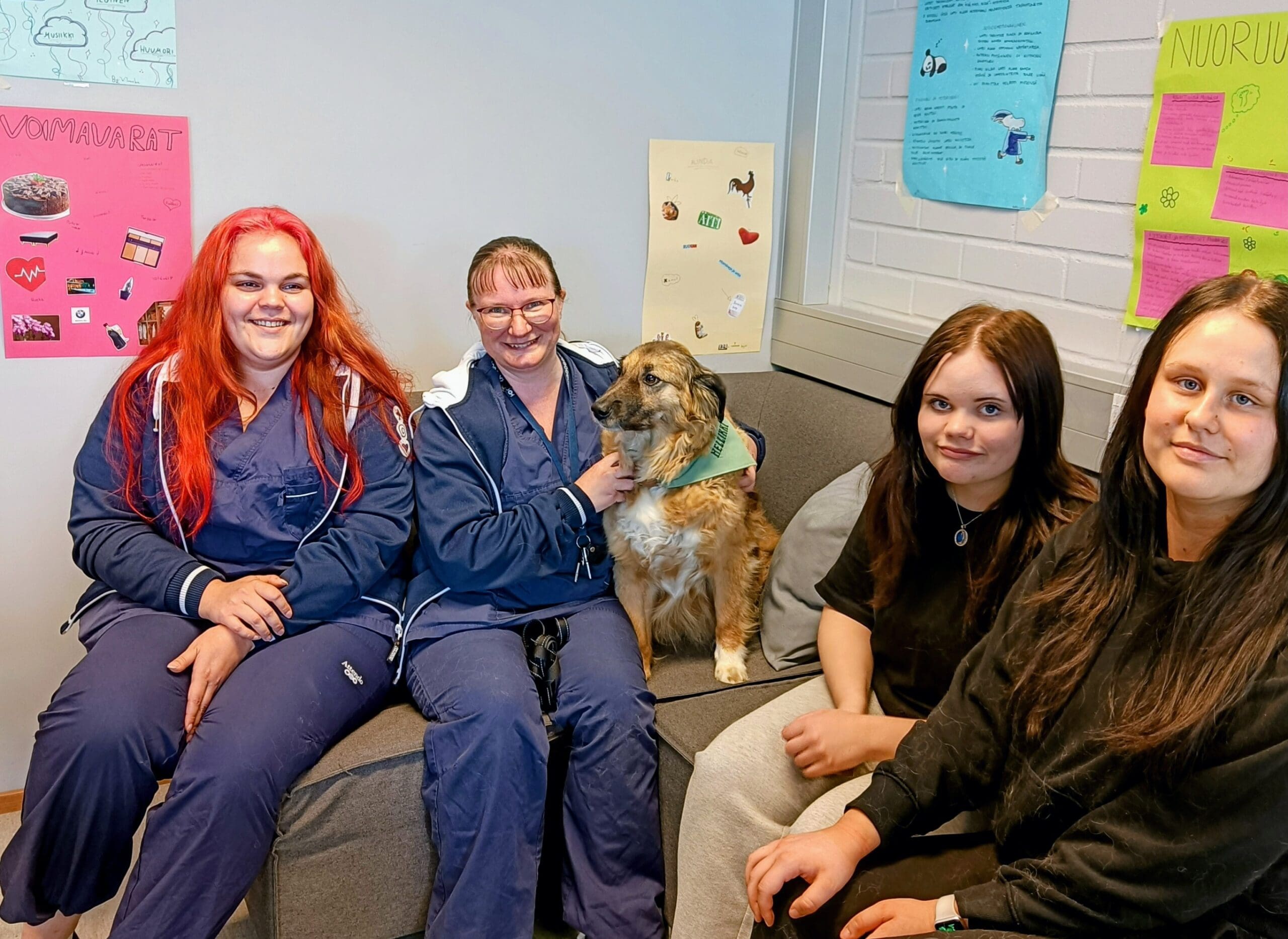 valokuva lähihoitajaopiskelijoista istumassa sohvalla sylissään koira